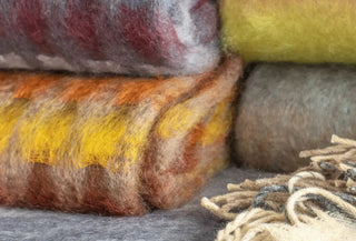 Detalle de mantas de mohair apiladas, destacando su volumen y acabado suave.