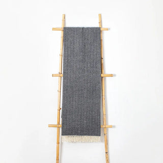 Manta de lana merino 100% con flecos blancos sobre escalera de madera. Real Fábrica