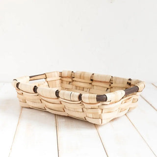 Foto de bandeja rectangular de castaño sobre una mesa de madera. Real Fábrica