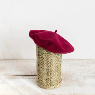 Boina de 100% lana merino colocada sobre un pedestal. Es de color vino, confeccionada de manera artesana por Elósegui. Real Fábrica.