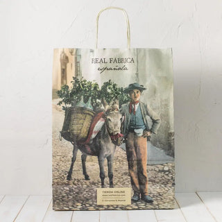 Bolsa de papel grande con imagen de un burrito y un niño a su lado, es ideal para un regalo en esos momentos especiales. Real Fábrica.