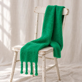 Bufanda chal de mohair verde con flecos sobre una silla. Hecha en Ezcaray