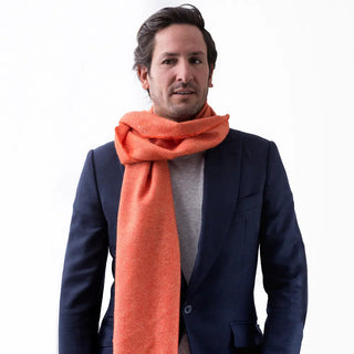 Foto de hombre luciendo nuestra bufanda naranja confeccionada en lana merino de la mejor calidad, de las ovejas de la Sierra de Grazalema, en Cádiz. Real Fábrica.