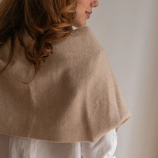 Foto de mujer de espalda luciendo nuestra elegante bufanda de lana merino color nuez de Grazalema. Real Fábrica