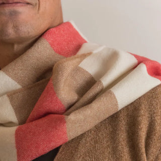 Foto de hombre mostrando nuestra bufanda de lana coral crudo y camel en su cuello. Real Fábrica