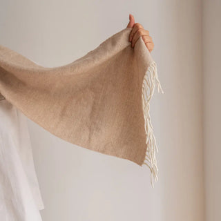 Bufanda de lana merino de color nuez, mano de mujer mostrando un extremo y los flecos de la bufanda. Real Fábrica