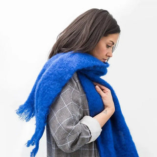 Mujer abrigada con una bufanda de mohair azul, una fibra de origen natural ultra cálida y ligera, de gran calidad. Real Fábrica. 