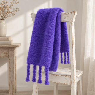 Bufanda de mohair azulina con flecos sobre una silla. Hecha en Ezcaray.