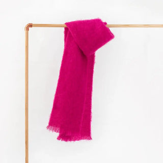 Una bufanda de mohair de color fucsia,  colgada sobre un perchero, tejido a mano por los artesanos de Ezcaray. Real Fábrica.