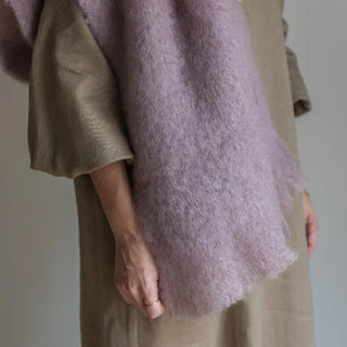 Mujer con una bufanda de mohair de color lila colgada en su hombro, tejido a mano por los artesanos de Ezcaray. Real Fábrica.