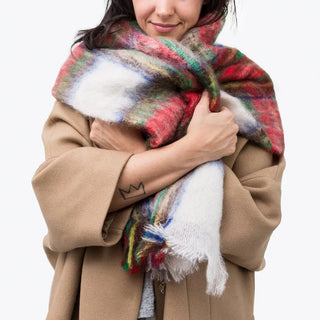 Mujer abrigada con un foulard de mohair tartán, una fibra de origen natural ultra cálida y ligera, de gran calidad. Real Fábrica. 
