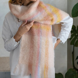 Foto de mujer abrigada con una suave y cálida bufanda tartán rosa,naranja y pastel. Real Fábrica.