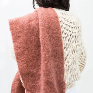 Foto de mujer de espalda con una bufanda de mohair de color teja que lleva sobre su hombro, una fibra suave y de gran calidad desarrollada por Ezcaray, en la Rioja. Real Fábrica.