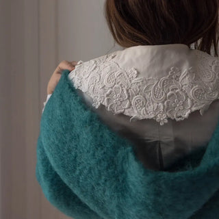 Mujer abrigada con una bufanda de mohair, una fibra de origen natural ultra cálida y ligera, de gran calidad. Real Fábrica. 