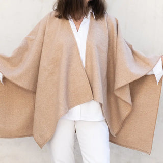 Foto de mujer luciendo muestra Capa ponchito de lana merino de color beige de Grazalema. Real Fábrica