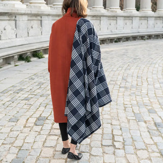 Foto de mujer llevando en su hombro nuestra Capa larga grazalema de cuadros azules. Real Fábrica