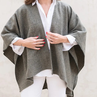 Foto de mujer luciendo muestra Capa ponchito de lana merino de color kaki de Grazalema. Real Fábrica