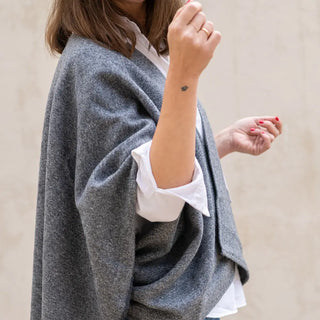 Foto de mujer de perfil luciendo nuestra Capa ponchito de Grazalema de color gris. Real Fábrica