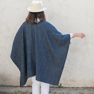 Foto de mujer de espalda luciendo nuestra Capa ponchito de lana merino gris oscuro. Real Fábrica