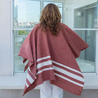 Foto de mujer de espalda luciendo muestra Capa ponchito color teja con rayas blancas de Grazalema. Real Fábrica