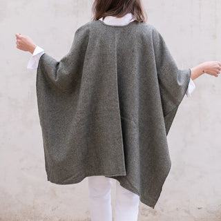 Foto de mujer de espalda luciendo nuestra Capa ponchito de Grazalema de color kaki. Real Fábrica