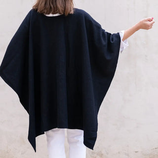 Foto de mujer de espalda luciendo nuestra Capa ponchito de Grazalema de color negro. Real Fábrica