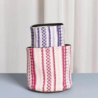 Foto de dos cestos Alpujarra de Eturel en dos colores rosado y morado, un organizador de tela con diseño tradicional para guardar productos de baño o cosmética. Real Fábrica.