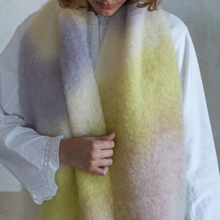 Foto de mujer abrigada con un suave y cálido Chal en colores pastel claros. Real Fábrica.