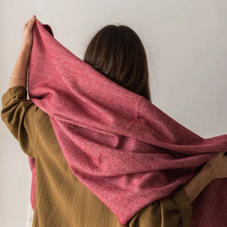 Foto de mujer de espalda tocando con sus dos manos nuestro Chal de lana merino elaboradas con productos de calidad y manos ¡Artesanas y estilosas!. Real Fábrica