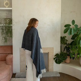 Foto de mujer de espalda luciendo nuestro chal de lana merino de Grazalema en color azul marino. Flecos anudados a mano. Real Fábrica. 