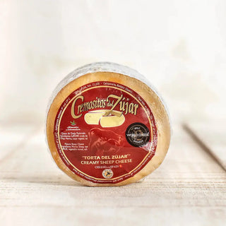 Foto frontal de un queso torta cremosito del Zújar sobre una mesa de madera. Real Fábrica