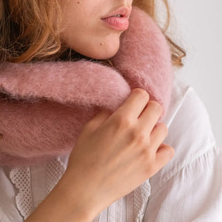 Mano de mujer agarrando el cuello de mohair rosa que lleva puesto. En el primer plano se aprecia la suavidad y la calidad del tejido artesano. Real Fábrica.