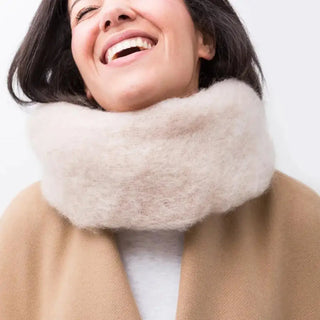 Mujer sonriente que lleva puesto un cuello hecho a mano de mohair, de color crudo. Real Fábrica.