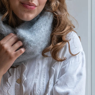 Mujer abrigada con un cuello de mohair color gris perla. Es cálido, suave y brillante. Real Fábrica.