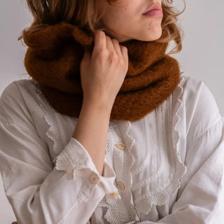 Mujer llevando un cuello de mohair de Ezcaray, que acaricia con una mano. El mohair es de primera calidad, muy suave y abrigado. Real Fábrica. 