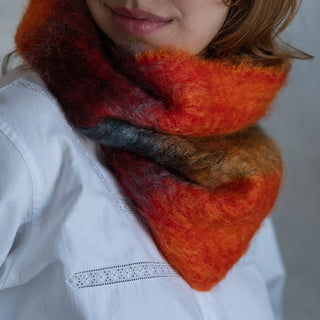 Modelo luciendo nuestro cuello en tonos rojo y naranja de mohair. En el primer plano se aprecia la suavidad y la calidad del tejido artesano. Real Fábrica.