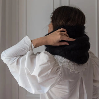 Mujer de espaldas abrigada y tocando un cuello de mohair. Real Fábrica.