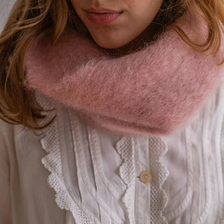 Mujer con un cuello de mohair rosa alrededor del cuello. Está tejido de forma manual por los artesanos de Ezcaray, en La Rioja. Real Fábrica.