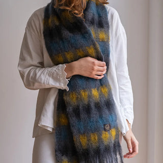 Foto de mujer abrigada con un suave y cálido foulard de cuadros mostaza y azul Klein. Real Fábrica.