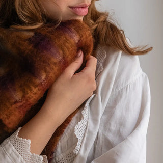 Mano de mujer acariciando la suavidad de un foulard de mohair con cuadros marrones y gris azulón. Real Fábrica.