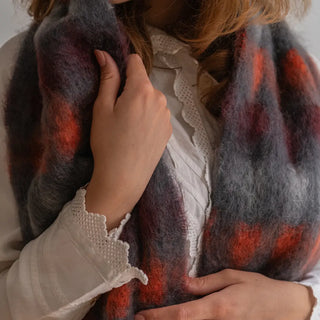 Mano de mujer acariciando un foulard de cuadros tejido en mohair, una fibra suave y cálida. Real Fábrica.