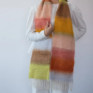 Foto de mujer abrigada con un suave y cálido foulard de franjas rosa y verde pastel. Real Fábrica.