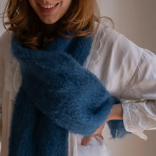 Mujer posando con un foulard de mohair en color azul. Su textura es muy suave y esponjosa. Real Fábrica.