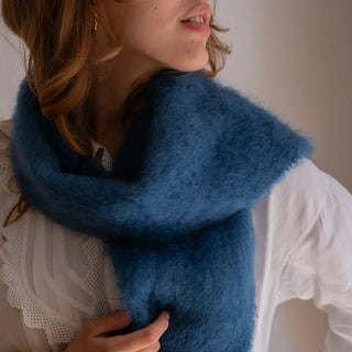 Plano detalle de un foulard de mohair en color azul alrededor del cuello de una modelo. Se aprecia la calidad y textura del tejido artesano. Real 