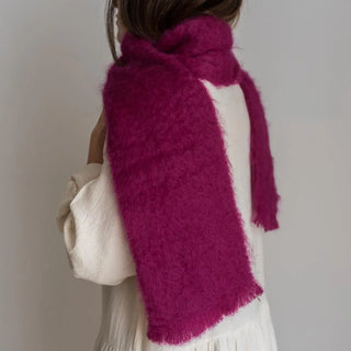 Una mujer toca con su mano el foulard de mohair buganvilla que lleva al cuello, una fibra suave y de gran calidad desarrollada por Ezcaray, en la Rioja. Real Fábrica.
