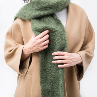Una mujer que lleva una bufanda de mohair muy calentita de color verde caqui, hecha a mano en La Rioja. Real Fábrica.