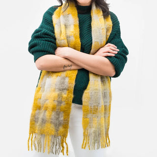 Una mujer que lleva una bufanda muy gordita y calentita. Está hecha de mohair con un patrón de cuadros de color amarillo.
