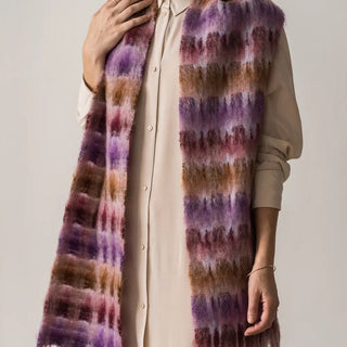 Mujer abrigada con un foulard de mohair de cuadros, una fibra de origen natural ultra cálida y ligera, de gran calidad. Real Fábrica. 