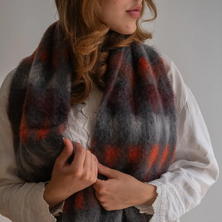 Mujer abrigada con un foulard de mohair artesano con un diseño de cuadros rojos. Real Fábrica.