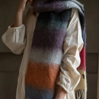 Mujer envuelta en un foulard  de franjas de mohair en 3 colores: azul, fucsia y blanco. El tejido artesano es de gran calidad, suave y muy cálido. Real Fábrica.